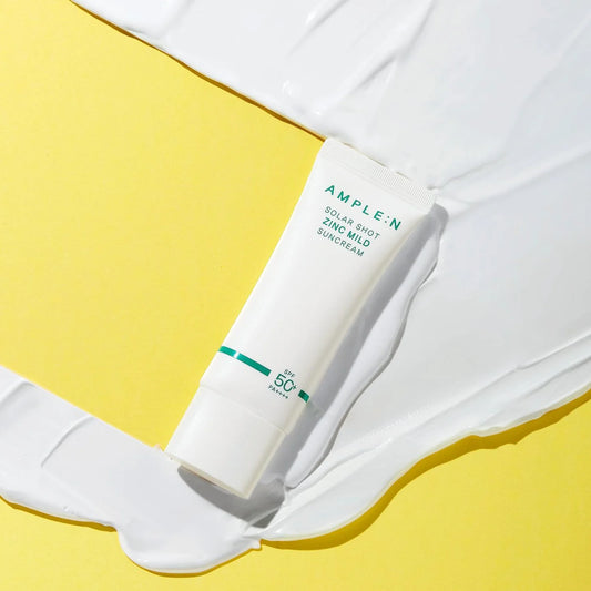 Tubo AMPLEN Zinc Mild sobre una muestra de crema blanca y fondo amarillo.