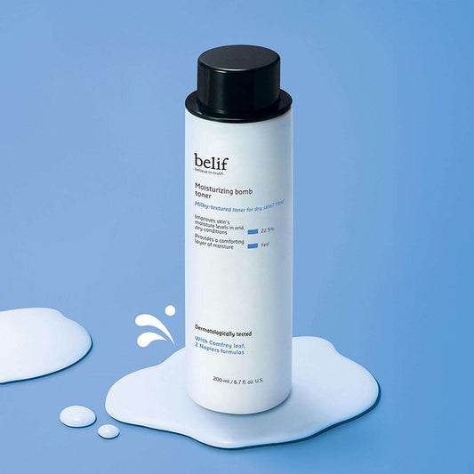 Botella de Belif Moisturizing Bomb Toner sobre una superficie de líquido blanco y fondo azul.