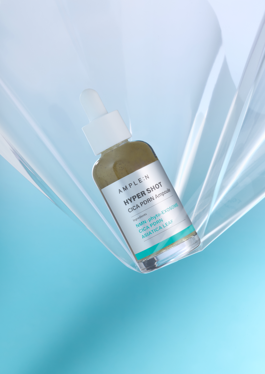 Frasco AMPLEN Hyper Shot Cica PDRN Ampoule de 50 ml sobre fondo celeste.